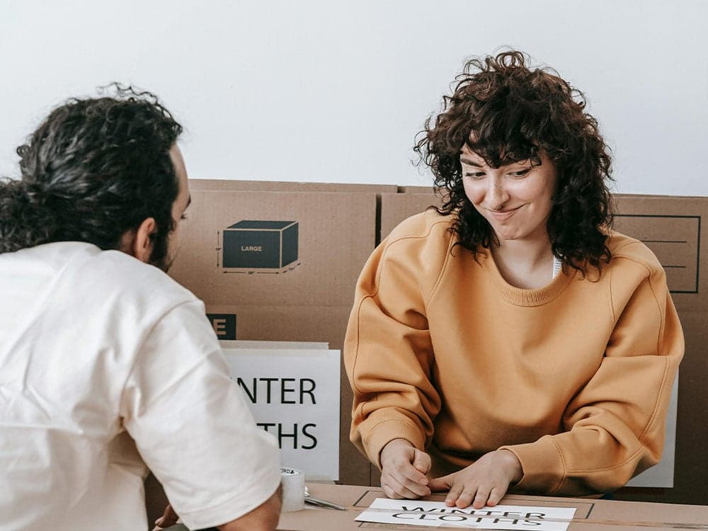 femme qui sourit devant un tas de cartons avant son déménagement